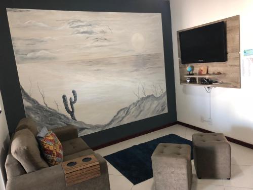 uma sala de estar com um sofá e uma pintura grande em Canto da Praia Suítes em Arraial do Cabo