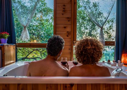 2 personnes assises dans une baignoire avec un verre de vin dans l'établissement Spa in The Woods - B&B in Amirim, à Amirim