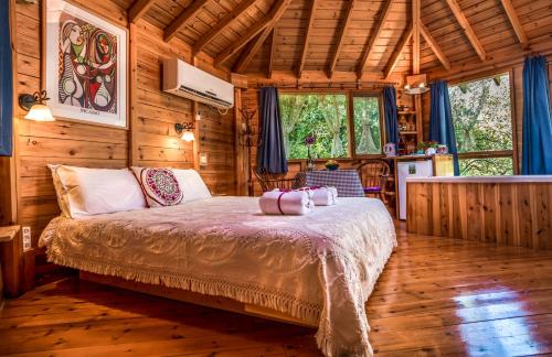 1 dormitorio con 1 cama en una cabaña de madera en Spa in The Woods - B&B in Amirim, en Amirim
