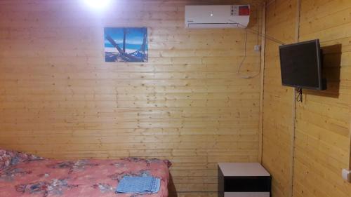 1 dormitorio con pared de madera, cama y TV en Motel MaksiM-4 DON en Pavlovsk