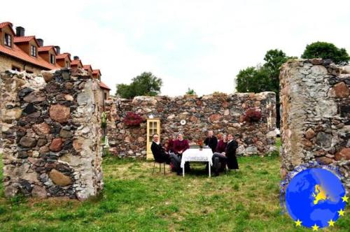 a group of people sitting at a table in front of a stone wall at Pakruojis Manor Hotel Miller's house in Pakruojis