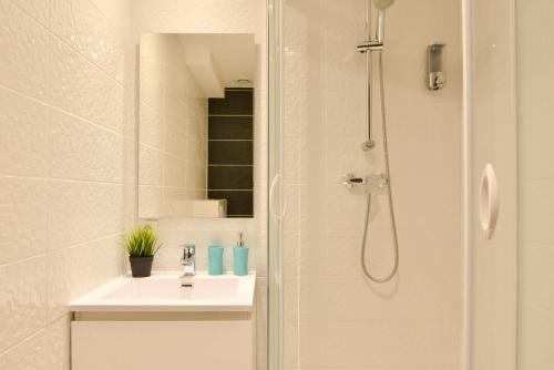 ein weißes Bad mit einer Dusche und einem Waschbecken in der Unterkunft Studio Ramblas Centre Toulouse in Toulouse