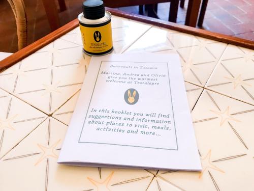 una botella de aceite esencial sentada en una mesa con un libro en Agriturismo Testalepre en Greve in Chianti