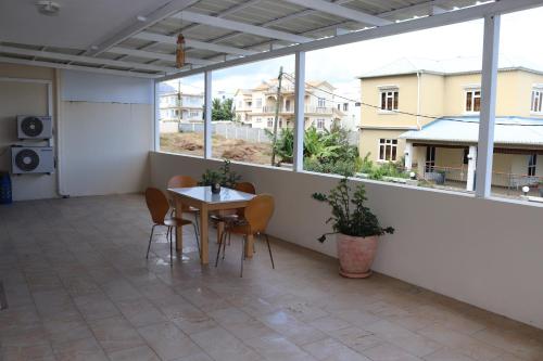 a room with a table and chairs and windows at Mahina Luxury 2 Bedroom Apartment with Pool in Flic-en-Flac