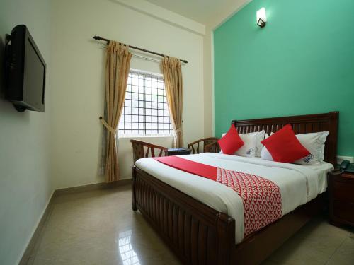 een slaapkamer met een bed met rode kussens en een televisie bij MGS Residency in Kallar Vattiyar