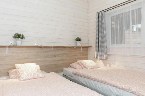 two beds in a room with a window and white walls at Domki "Arkadia" in Pobierowo