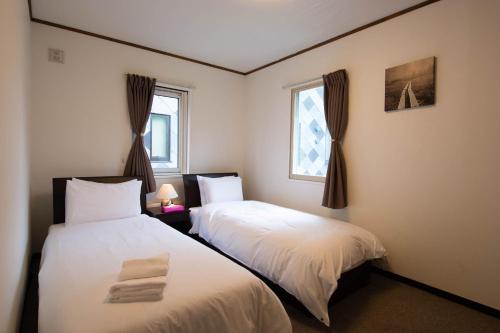two beds in a room with two windows at Yukon in Kutchan