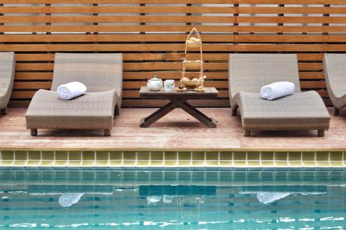 two chairs and a table next to a swimming pool at Bamboori Boutique Resort in Chiang Mai