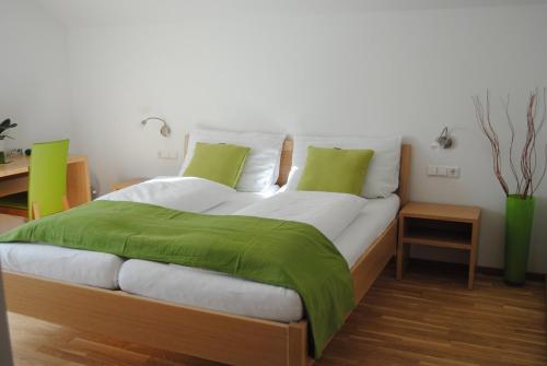 a large bed with green sheets and pillows at Weingut Schlafgut Genussgut Lorenz in Kitzeck im Sausal