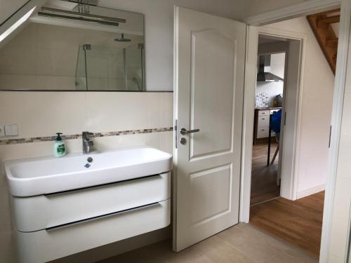 ein Badezimmer mit einem Waschbecken, einem Spiegel und einer Tür in der Unterkunft Dachgeschosswohnung in Lörrach