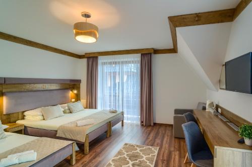 a hotel room with two beds and a tv at Dom Wypoczynkowy Stokrotka in Białka Tatrzanska