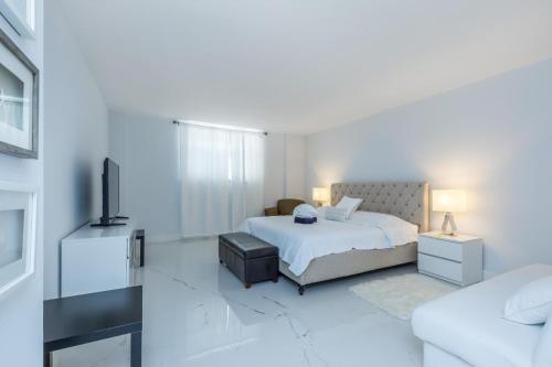 ein weißes Schlafzimmer mit einem Bett und einem TV in der Unterkunft Two bed beach condo at Sian Miami in Hollywood