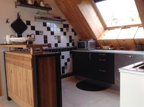 a kitchen with black and white tiles on the wall at Chez MARLENE in Quettehou