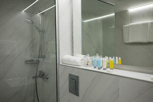 a bathroom with a shower and a sink and a mirror at Pefkos City Hotel in Limassol