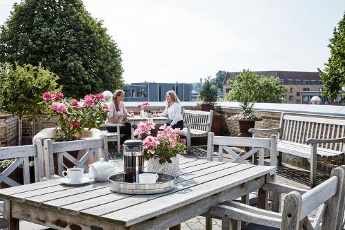 a wooden table with flowers on a patio at Montra Odder Parkhotel in Odder