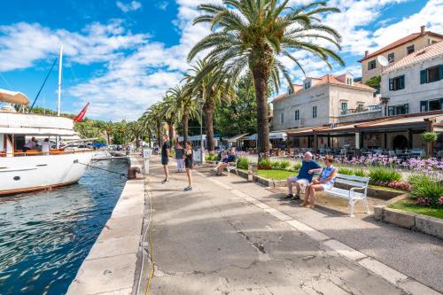 a group of people sitting on benches next to a boat at Boutique B&B Villa Faggioni in Cavtat