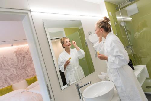 a woman standing in front of a mirror brushing her teeth at Hotel Weiss Kreuz in Thusis