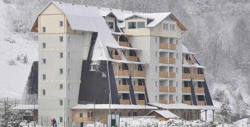 a large building with snow on top of it at Sunčani Apartman in Brzeće