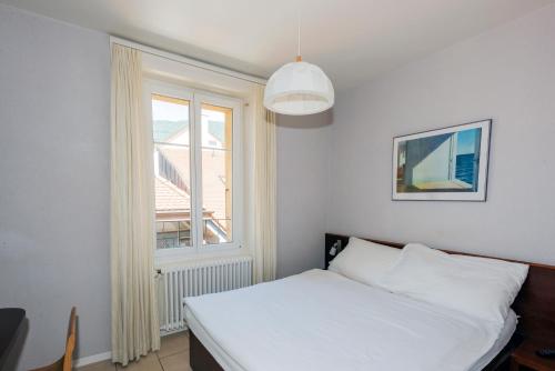 a bedroom with a white bed and a window at Hôtel du Cheval-Blanc in Saint-Blaise