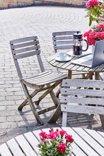 a wooden table and chair with a table with a laptop at Montra Odder Parkhotel in Odder