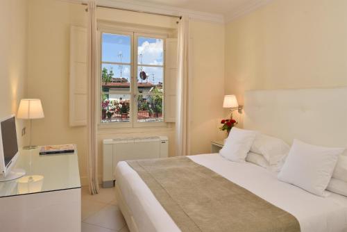 a white bedroom with a bed and a window at Residenza Fiorentina in Florence