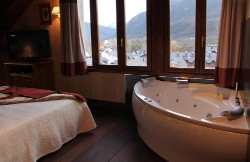 a bathroom with a tub in a room with windows at Hotel Pradas Ordesa in Broto