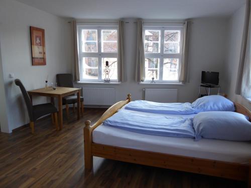 リューネブルクにあるFerienwohnung am Liebesgrundの窓2つとテーブルが備わるドミトリールームのベッド1台分です。