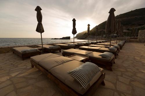 a row of beds with umbrellas on the beach at Folie Marine Hotel & Beach Club in Jal