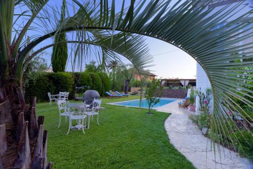 - un jardin avec une table, des chaises et une piscine dans l'établissement Villa Tranquille, à Vence