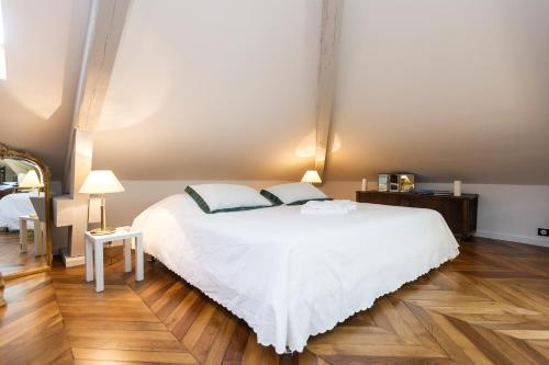 Un dormitorio con una gran cama blanca y suelos de madera. en Villa Tranquille, en Vence