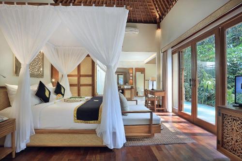 a bedroom with a bed with a canopy at The Sankara Suites and Villas by Pramana in Ubud