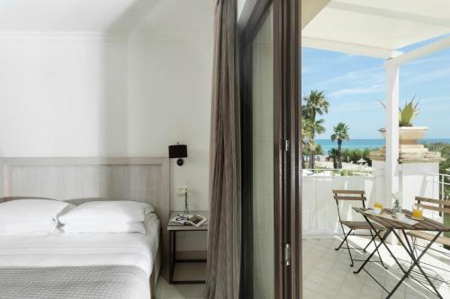 a bedroom with a bed and a balcony with the ocean at Canne Bianche Lifestyle Hotel in Torre Canne