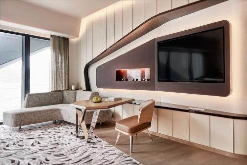a living room with a table and a tv at City of Dreams - Morpheus in Macau