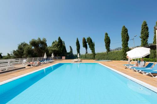 una piscina en una villa con personas sentadas en sillones en Quinta do Estreito en Estreito de Câmara de Lobos