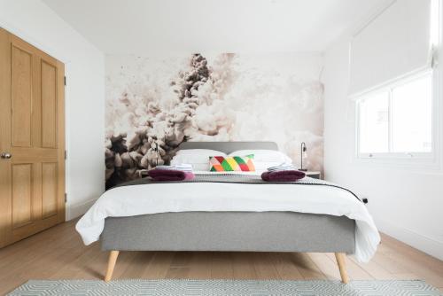 a bedroom with a bed with white walls at The Old Tailor House - Charming 4BDR Home in Oxford