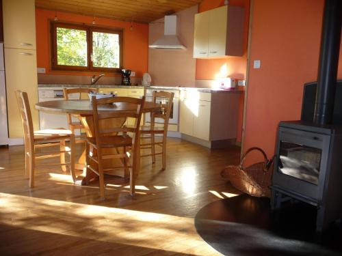 una cocina con mesa y sillas y una cocina con paredes de color naranja. en 8 Chalets - Les Lodges du Hérisson - à 1500m des cascades, en Bonlieu