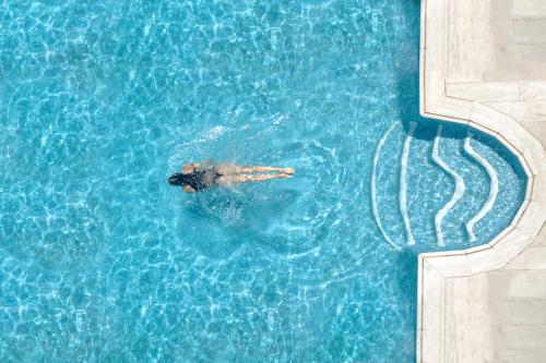 a person is swimming in a swimming pool at Harmony Boutique Hotel in Mýkonos City