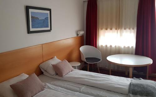 Glomfjord的住宿－Glomfjord Hotel，一间卧室配有一张床、一张桌子和一个窗户。