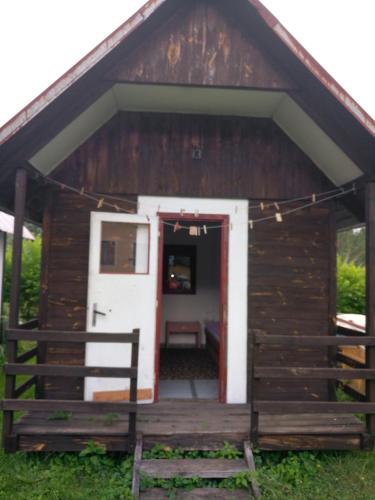 a wooden cabin with a white door and a porch at Rekreacni stredisko u Kralicke chaty in Staré Město