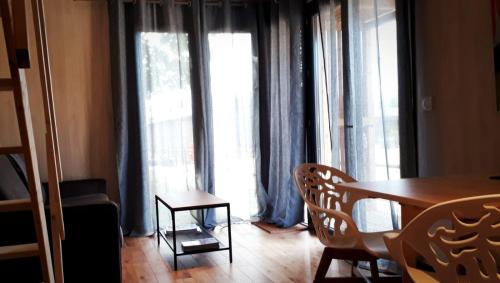 a dining room with a table and chairs and large windows at Manège de la Chapinière - DadaLoge tiny-house in Châteauvieux