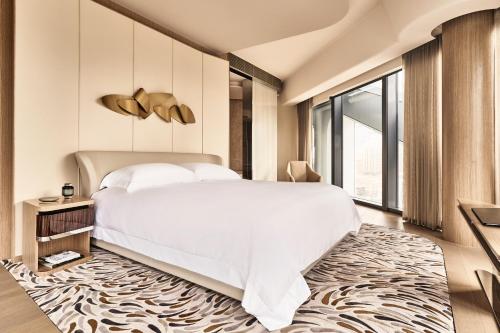 a bedroom with a large white bed and a large window at City of Dreams - Morpheus in Macau