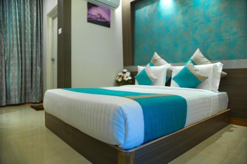 a bedroom with a large bed with blue and white pillows at Aishwarya Le Royal in Mysore