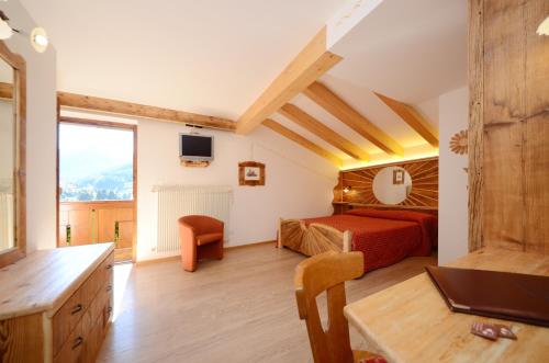 a bedroom with a red bed and a large window at Hotel La Soldanella in Moena