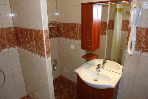 y baño con lavabo y ducha. en HoldLux Apartmanok, en Sárvár