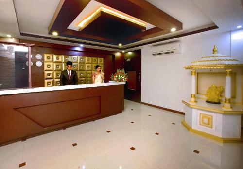 two people standing at a counter in a room at Sr Palaceinn in Kolattupuzha