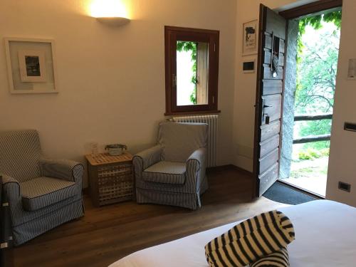 ein Schlafzimmer mit 2 Stühlen, einem Bett und einem Fenster in der Unterkunft Agriturismo La Tensa in Domodossola