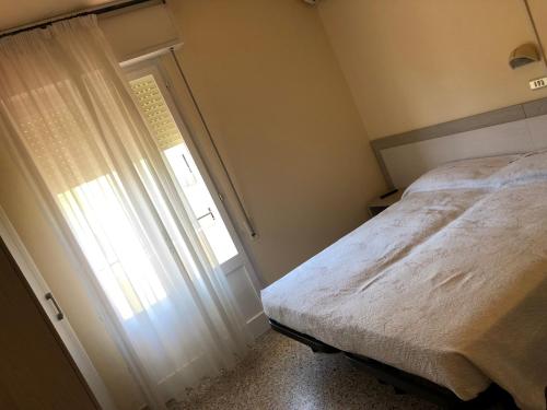 um pequeno quarto com uma cama e uma janela em Hotel Ines em Cesenatico