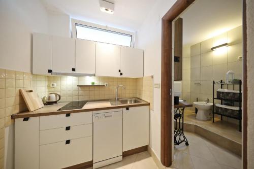 a kitchen with white cabinets and a sink at Apartmani Olivia in Bibinje
