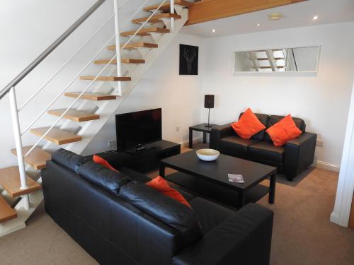 a living room with black leather furniture and a staircase at Princes Dock Chambers 8 in Hull