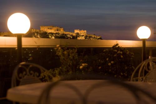 a table with two lights and a castle in the background at Arethusa Hotel in Athens